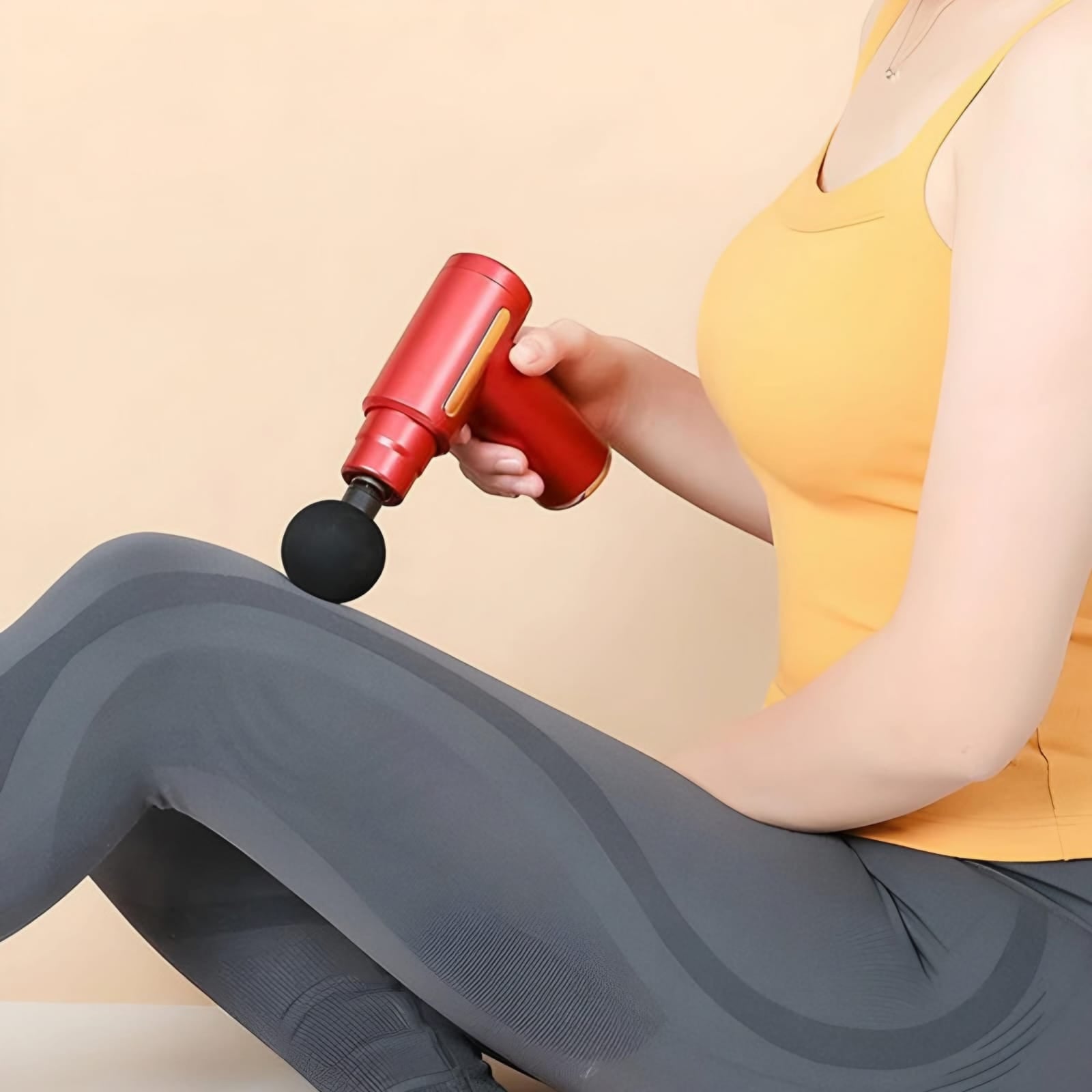 Person using a red massage gun on their leg against a beige background